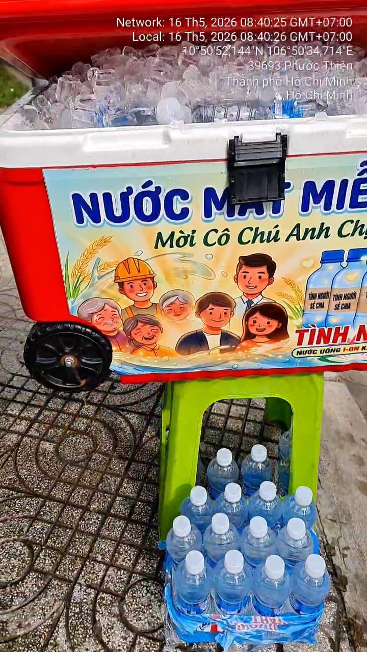 Thùng nước lạnh miễn phí mỗi sáng cho cư dân, hỗ trợ người đi đường giữa trời nóng. Không cần mua, ai khát đều có thể lấy.