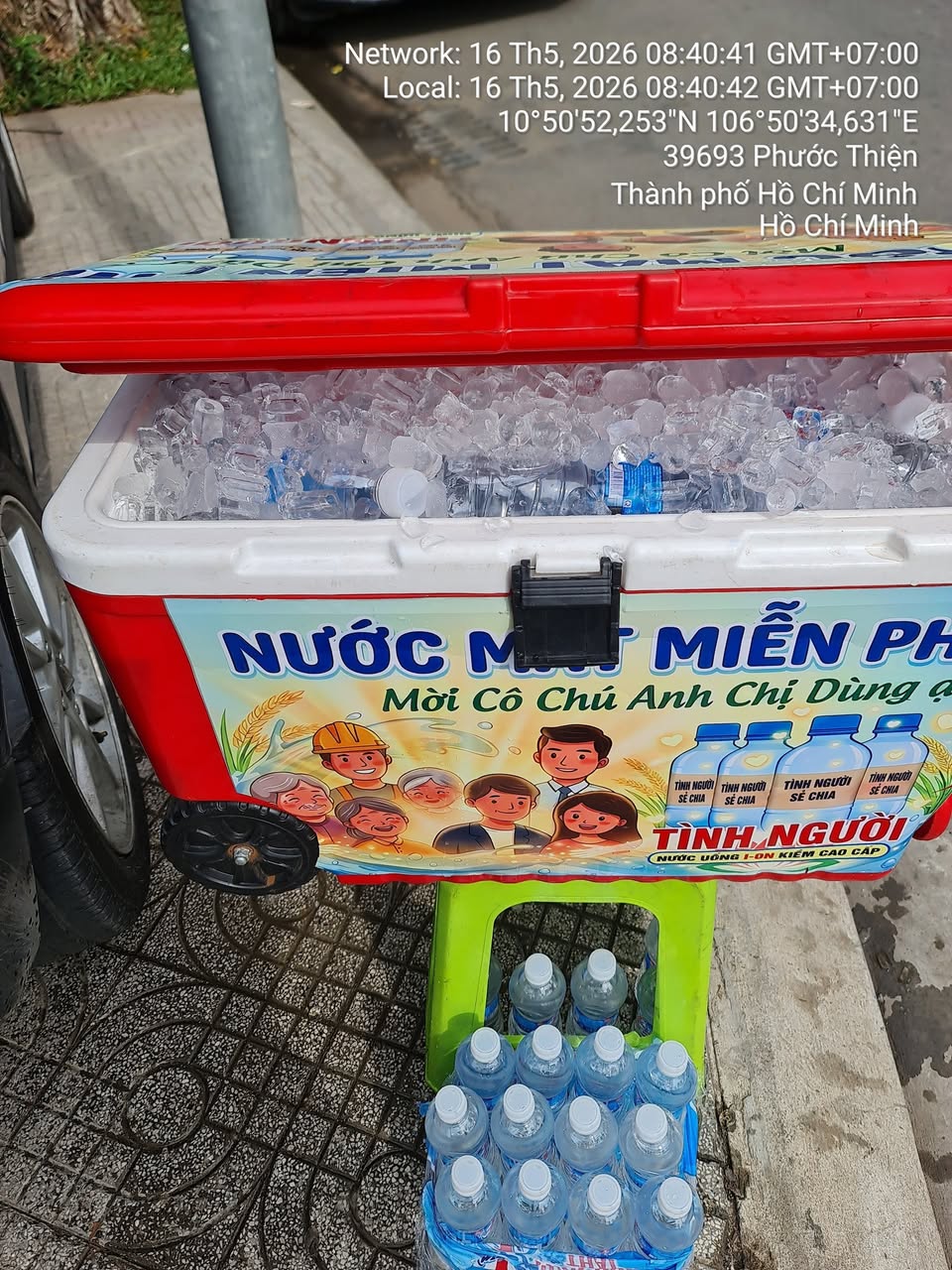Thùng nước lạnh miễn phí mỗi sáng cho cư dân, hỗ trợ người đi đường giữa trời nóng. Không cần mua, ai khát đều có thể lấy.